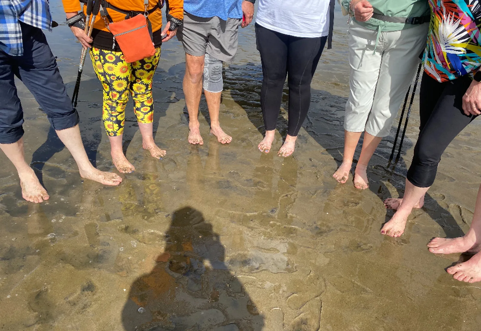 Bare feet of walkers standing in the shallow water of the tidal crossing