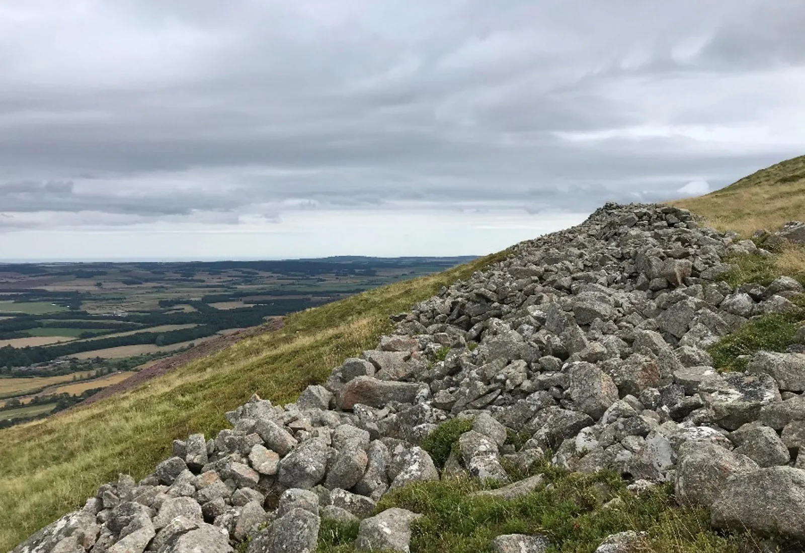 The stone rampart scree and summit of Yeavering Bell with views over the Cheviot foothills